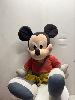 The toy stands approximately 24–25 inches (about 60–63 cm) tall. Clothing: The character wears a signature red T-shirt featuring a round "M Mickey" lo