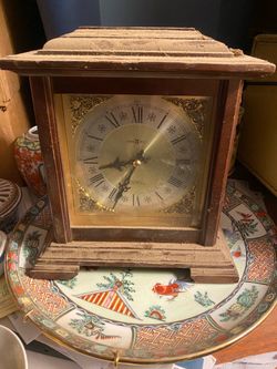 Howard Miller quartz chiming mantel clock (such as the Medford model 612-481 or a similar bracket style) featuring a wooden case, brass-finished dial