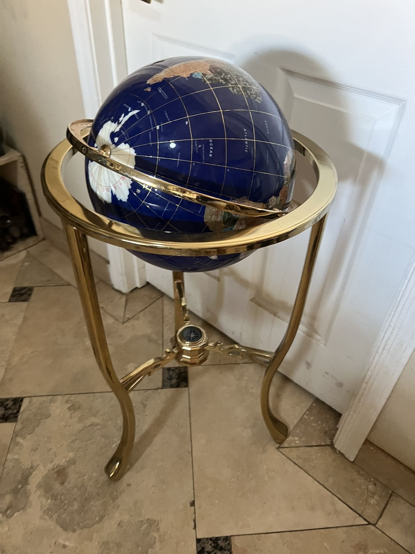 Decorative gemstone globe with gold stand and compass. Luxury collectible.