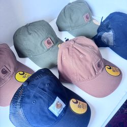 New Carhartt hats available. Multiple colors green, brown, black. Some hats are trucker style with mesh back, others are solid. All hats have original