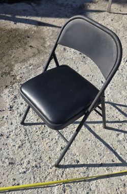 Black vinyl-padded metal folding chair featuring a curved backrest and a cushioned seats//13 chairs &1 table