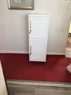 White metal storage cabinet with brass handles