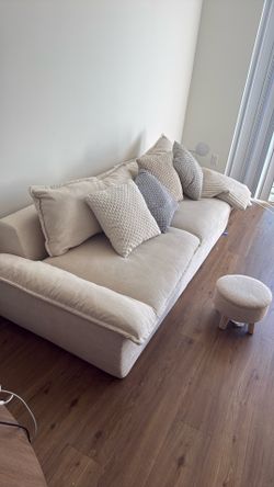 Cream boneless couch with throw pillows, quilted throw blanket, and matching ottoman