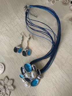 Earth-toned jewelry set includes a multi-strand cord necklace and matching drop earrings. The pieces have a square mosaic design with brown and cream 