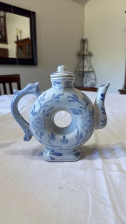 Vintage blue and white ceramic donut-shaped teapot with dragon handle.