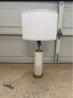 This Brightech Arden LED table lamp features a white marble cylinder base and brass-finished accents.