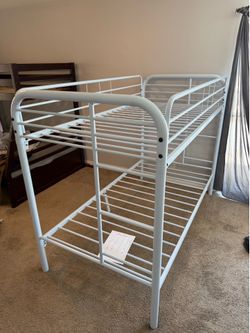 White metal twin bunk beds w/ mattresses and sheets and blankets