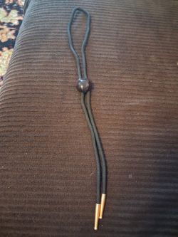 black braided cord bolo tie with a dark stone slide and gold-tone tips.