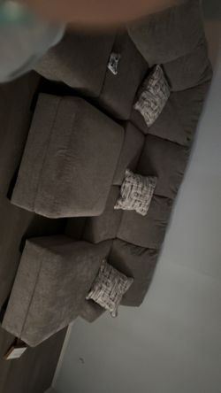 Gray sectional couch with pillows and ottoman