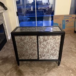 Black console table or cabinet featuring botanical or floral glass panels