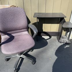Upholstered adjustable office chair with armrests and wheels, and small, laminated particle board desk with side shelves. 