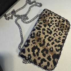 Chic leopard print crossbody bag with a silver chain strap. Features a bold tan and black pattern for a stylish look. Lightweight and versatile for da