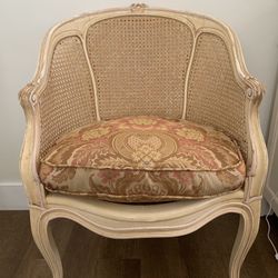 Vintage French Provincial armchair with distressed white frame and cane detailing.