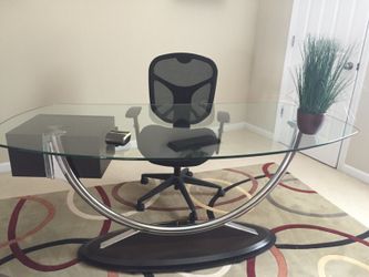 Thick glass office desk with an ergonomic mesh black chair
