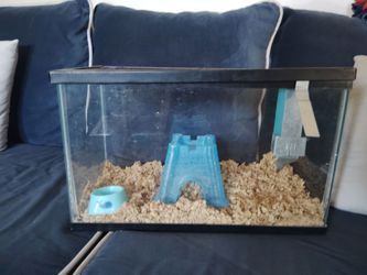 A big hamster cage with water bottle, a castle, and a bowl