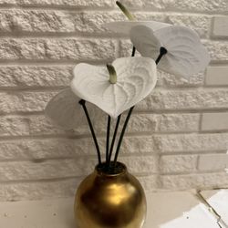Elegant gold vase with artificial white flowers.