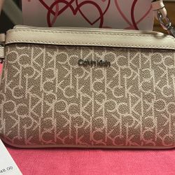 Calvin Klein monogram print wristlet in a cream and beige color scheme. 