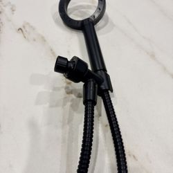 Black handheld shower head with a flexible hose and connection point.