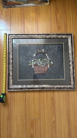 Decorative embossed metal relief artwork behind glass.