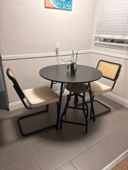 Round Black Dining Table with Two Cane Chairs