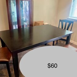 Black wood dining room table with 4 black chairs and one bench