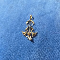 An antique Art Nouveau or Edwardian pendant in 10k yellow gold, featuring seed pearls and a small central diamond.
