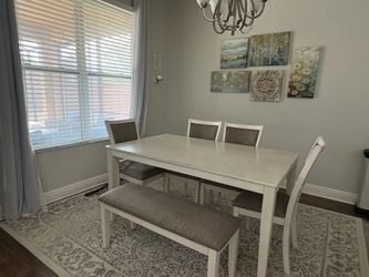 White dining table with four chairs and a bench.