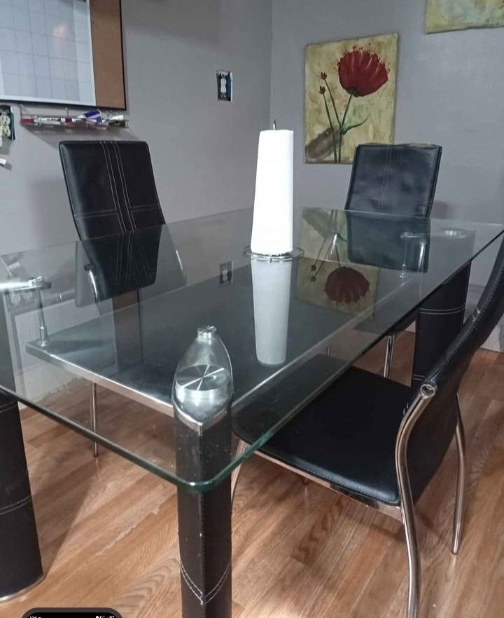 A Black Glass Table With Three Chairs