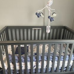 GREY CRIB WITH MOBIL AND SHEETS 