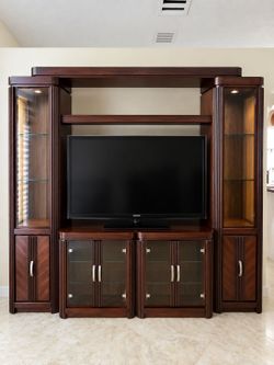 Large dark wood entertainment center with glass display cabinets and TV stand.