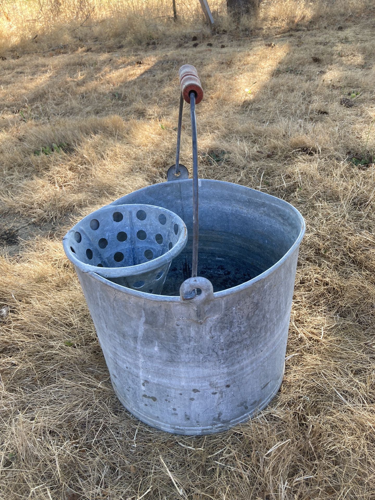 Vintage galvanized mop bucket with strainer.