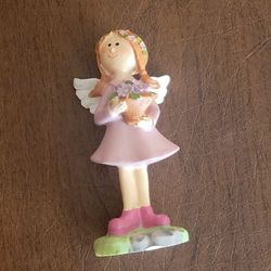Small decorative figurine of a stylized angel holding a basket of 
flowers. Made in Germany. New, with tag
Design: Features a girl angel with orange h