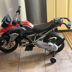 This item is a Rollplay BMW R 1200 GS 6V kids' ride-on electric motorcycle in red and gray.     