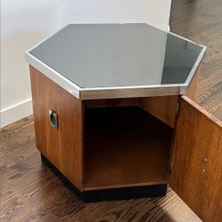 Mid Century Hexagonal Chrome Accent Side Table/ Cabinet. It consist of smoked glass top with chrome trim and hinged door, it rests on a plinth base. I