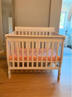 White mini crib with mattress