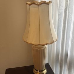 vintage table lamp from 1994, featuring an ivory-colored ceramic base with vertical fluting, a brass-finished pedestal base, and a pleated scalloped l