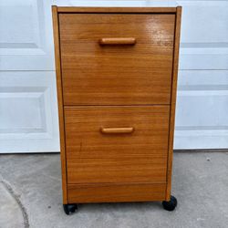 vintage Danish Modern teak wood filing cabinet featuring two drawers with integrated pulls and casters for mobility.
