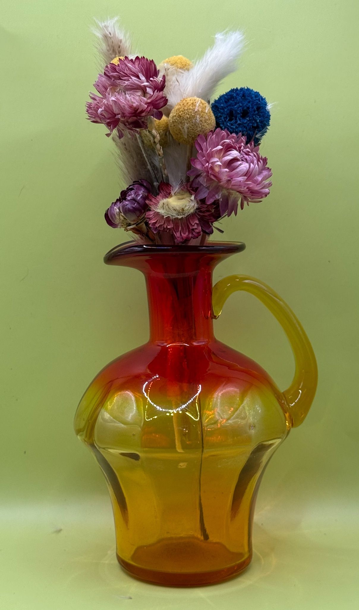 exquisite amberina red, orange, and yellow crackle glass pitcher is a testament to the timeless beauty of mid-century modern design.