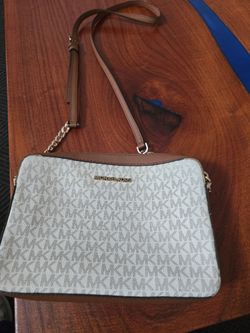 Michael Kors crossbody with signature MK print. Gold-tone logo and hardware. Brown leather trim and adjustable strap. Compact and chic for daily wear.