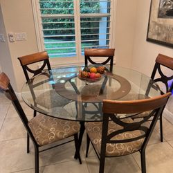Contemporary 5-piece round dining set featuring a glass tabletop, a metal base, and upholstered chairs w/ a circular pattern design