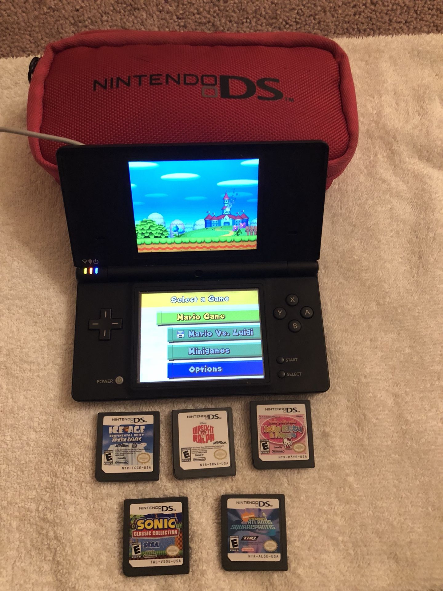 Nitendo DS with charger case and 6 games -Super Mario, Sonic, Wreck it Ralph, Sponge Bob Atlantis, Ice Age and Hello Kitty