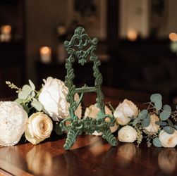 Vintage ornate cast iron tabletop easel features a decorative scroll design with a green, weathered patina