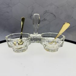 Art Deco salt and pepper cellar set likely from around the 1920s. It is made of glass and features a two-bowl design with a central handle. It is ofte