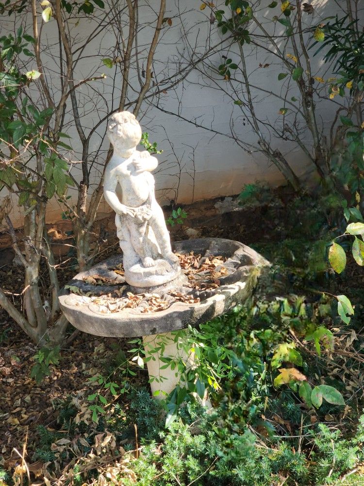 vintage concrete birdbath featuring a cherub statue