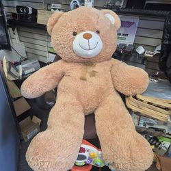 light brown plush teddy bear with a dark brown ribbon bow around its nec