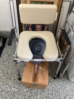 Medline Padded Bedside Drop-Arm Commode, which features dropdown armrests to assist with lateral transfers and a thick foam-padded beige seat.