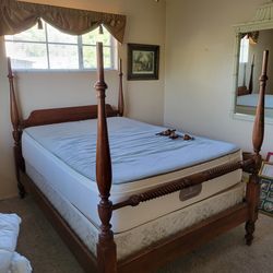 Wooden four-poster bed frame with turned posts and rope carving.