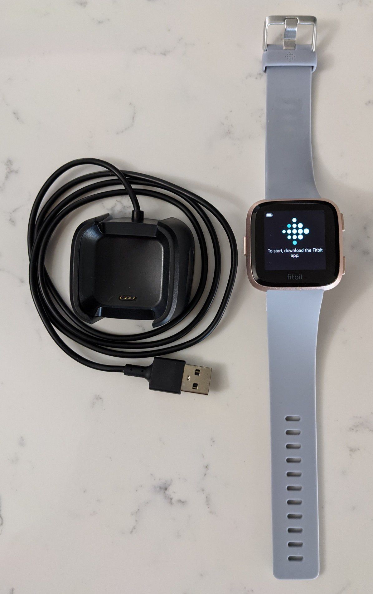 Fitbit versa rose gold with charging cable and grey band