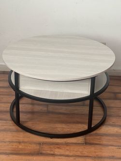 Round adjustable white coffee table that has a storage