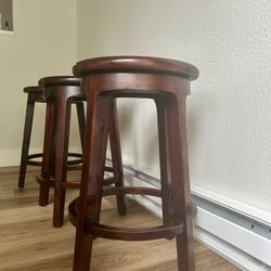 Three 24” Tall Cherry brown swivel top barstools 